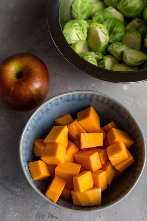 Bowl of chopped squash, halved sprouts and an apple.