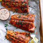 Baked Cajun Salmon With Spicy Tartar Sauce on the baking tray with lemon wedges.