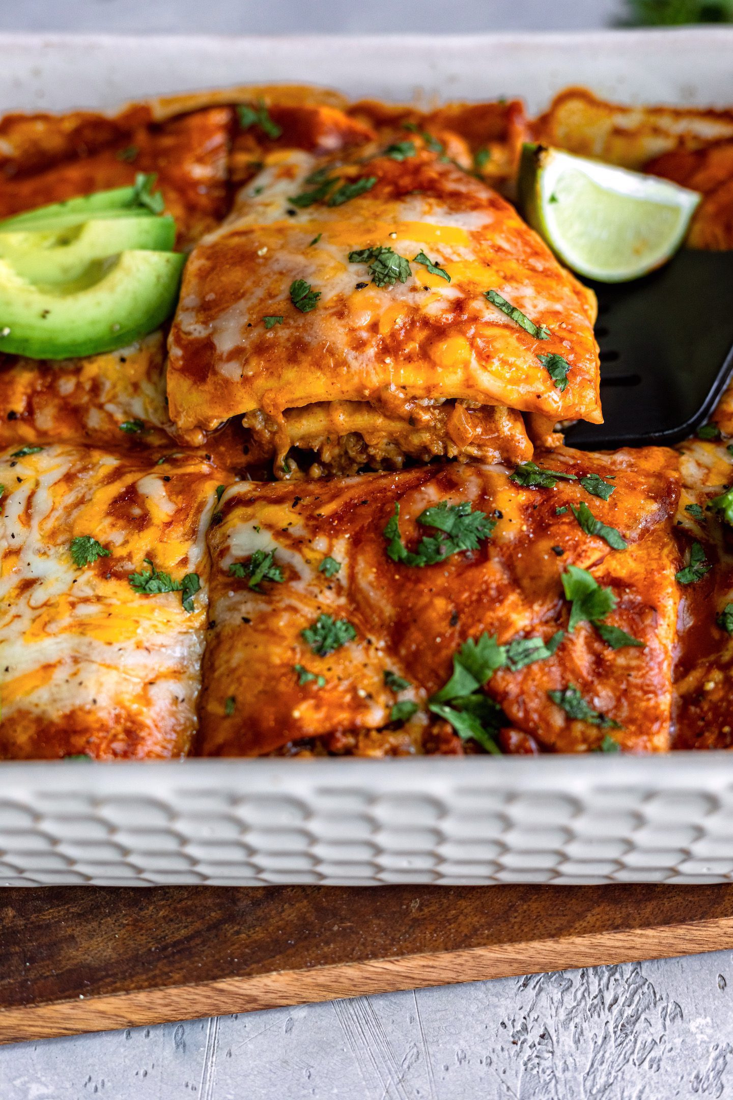 Close up of a slice being lifted out of an enchilada casserole.