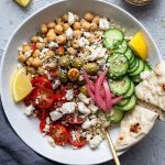 Greek salad bowls with chickpeas, salad, feta, olives and pickled onions.