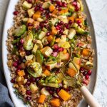 Close up of a fall farro salad with roasted squash, Brussels sprouts, walnuts and pomegranate.