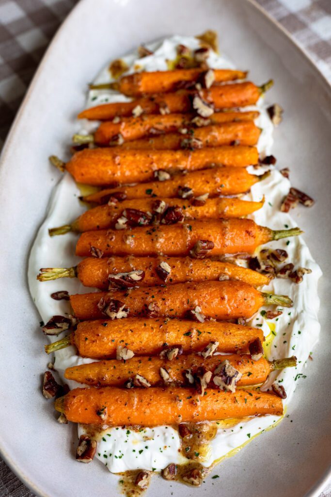 Roasted baby carrots with a maple mustard glaze, topped with chopped pecans and served atop whipped goat cheese.