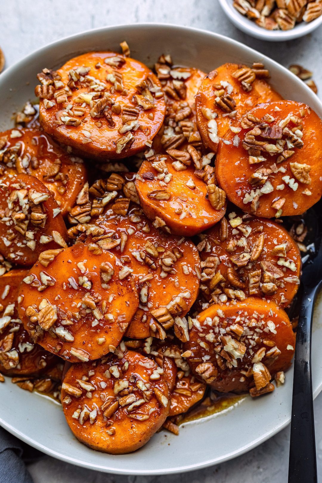 A heaping plate of CrockPot Maple Bourbon Candied Sweet Potatoes, topped generously with chopped pecans.