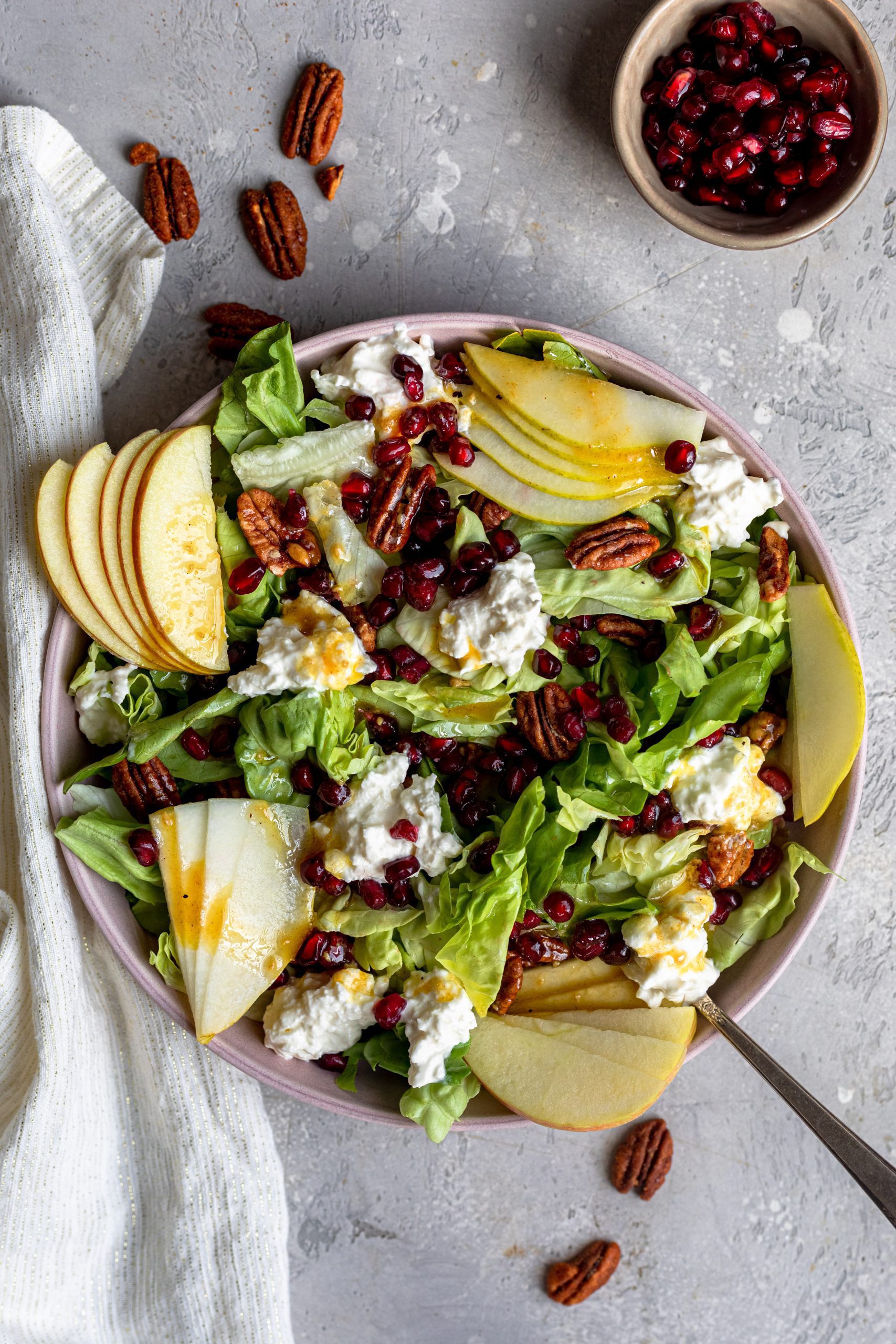 A large bowl filled with vibrant salad, topped with fresh fruit and burrata. 