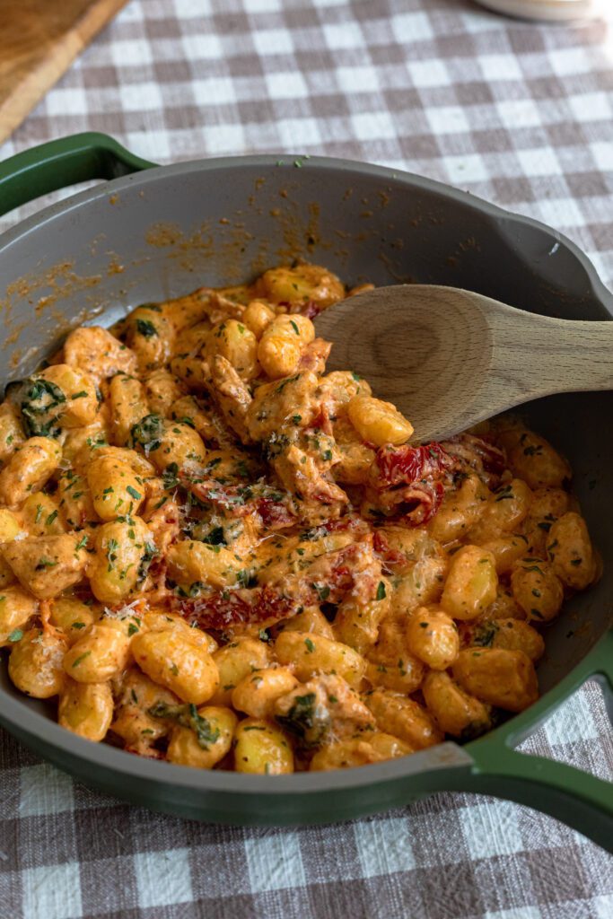 A dish of homemade marry me chicken and gnocci in a creamy sauce with cooked tomatoes, freshly grated parmesan and chopped basil.